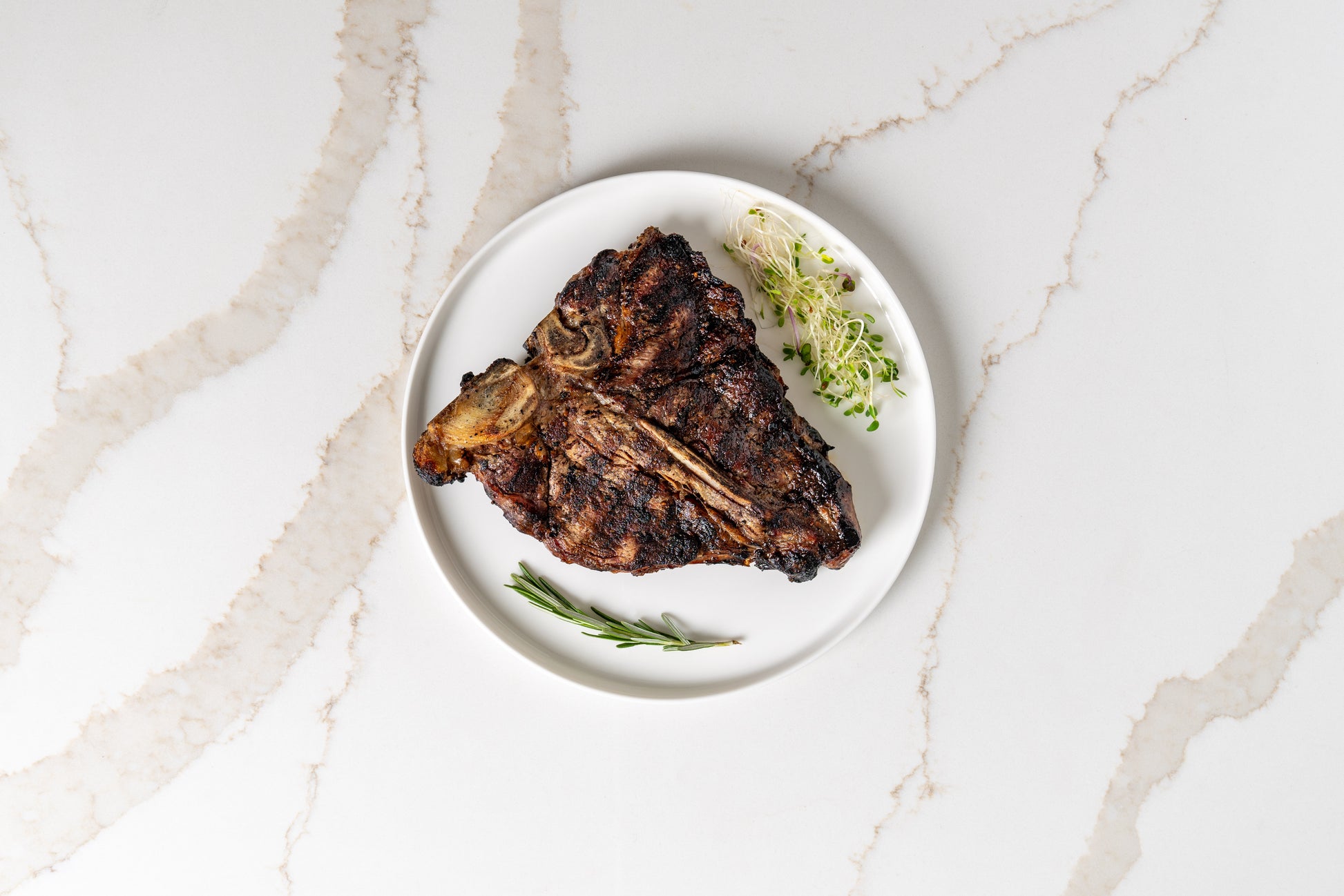 Seared Kansas T-bone steak on plate – premium sprout-finished beef.